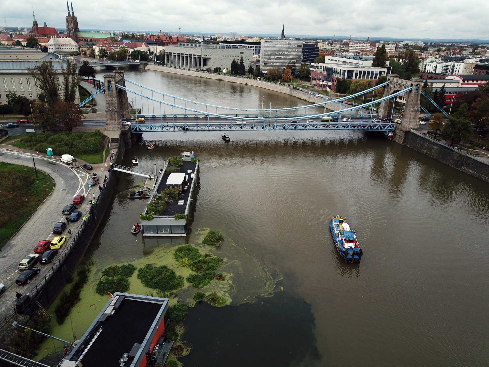 Widok na Odrę z powietrza. Po lewej stronie widoczny budynek Odra Centrum, po prawej nieduży statek. Dalej widoczny jest most Grunwaldzki, Biblioteka Uniwersytecka i panorama Wrocławia. 