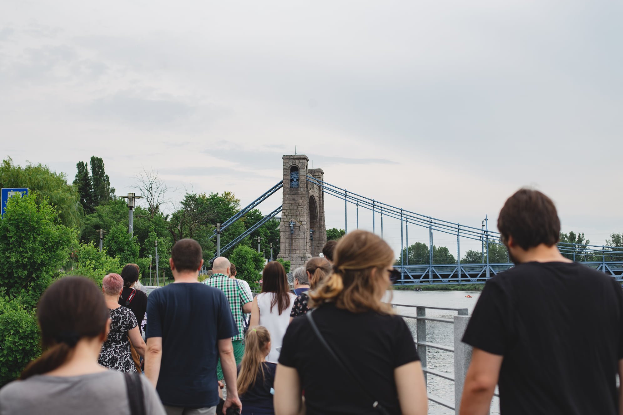 Grupa ludz spaceruje wzdłuż Odry. Za nimi w tle widoczny most Grunwaldzki.