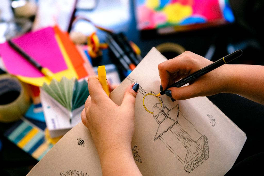 zdjęcie: materiały organizatora Kolorowa fotografia przedstawia osobę kolorującą mazakami rysunek.