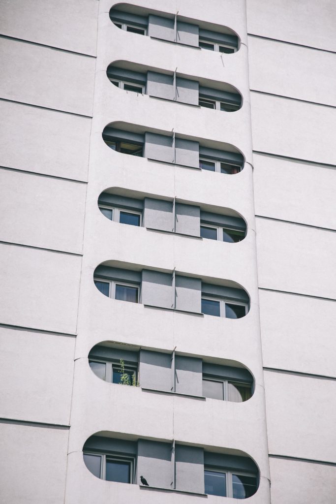 Fragment elewacji wieżowca - charakterystyczne zaokrąglone okna na tle białej elewacji.