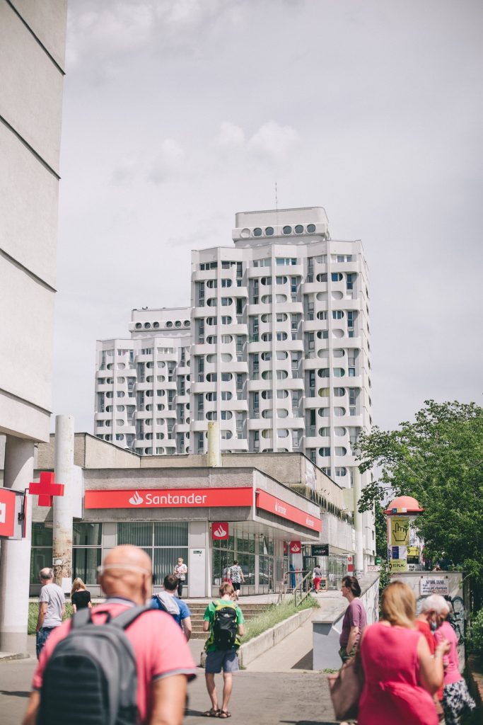 Widok na wrocławskie sedesowce z charakterystycznymi okrągłymi oknami. Na pierwszym planie widoczny szeroki chodnik pełen ludzi.