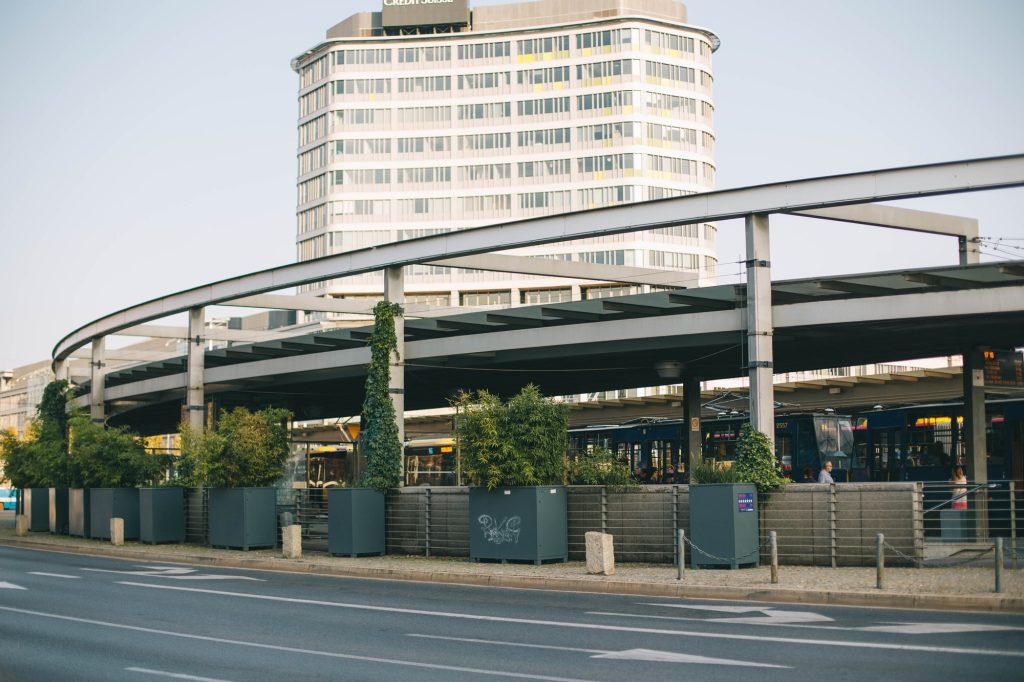 Widok na rondo Reagana i znajdujące się na nim przystanki autobusowo-tramwajowe. W tle wysoki wieżowiec.
