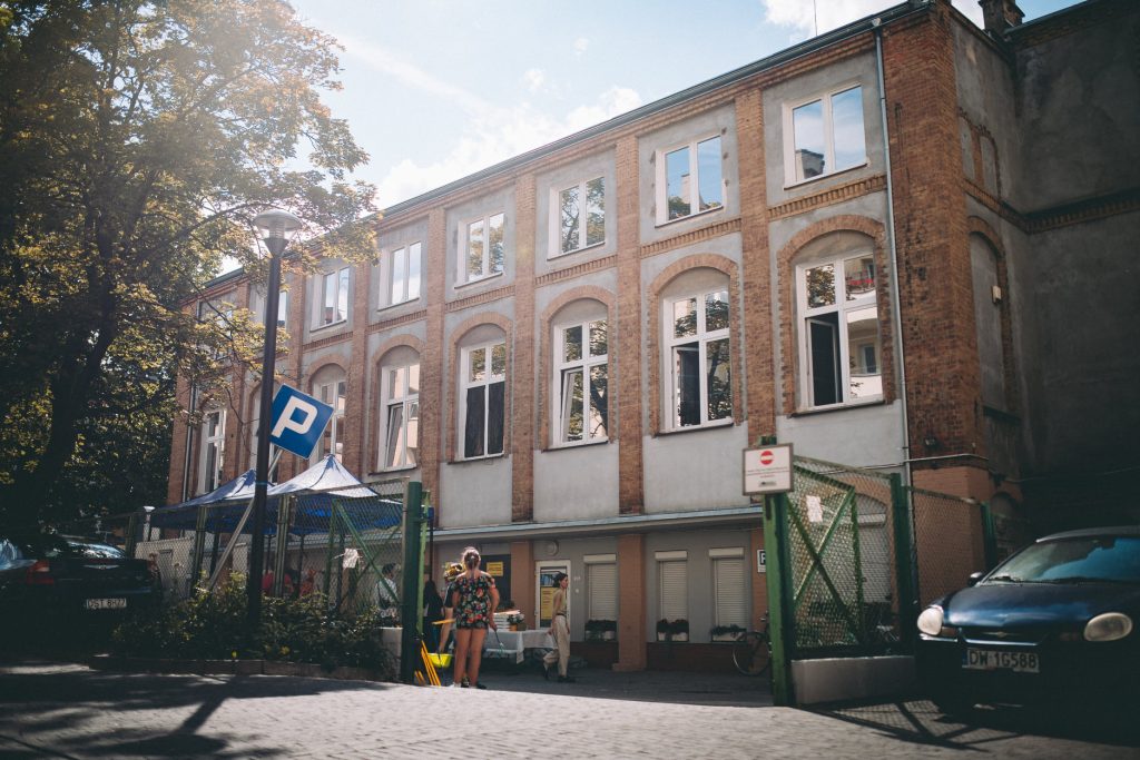 Widok na budynek z czerwonej cegły, stojący przy Curie 63a. To tu znajduje się Centrum Aktywności lokalnej Plac Grunwaldzki OD NOWA.
