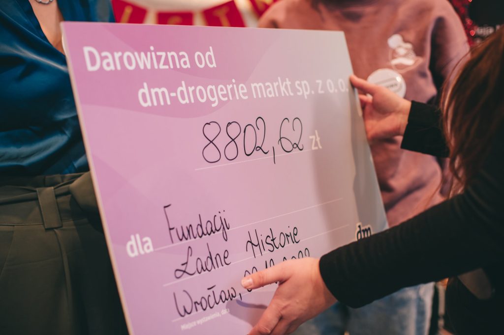 zdjęcie: Marta Sobala Kolorowa, pozioma fotografia: zbliżenie na duży, różowy czek dla Fundacji z darowizną od drogerii dm w wysokości 8802,62 zł.