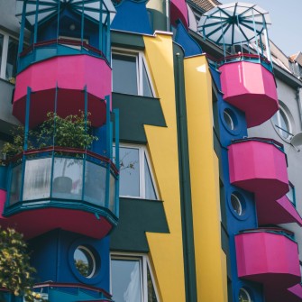 Plomba architektoniczna wybudowana w 1996 roku według projektu architekta Wojciecha Jarząbka. Nazywana także “Papugowcem”. Charakterystyczna elewacja składa się z geometrycznych i prostokątnych elementów, a także przeszklonych balkonów. Fotografia pochodzi z okresu po odnowieniu budynku, gdy pierwotny kolor czerwonego wina zastąpiono różowym.