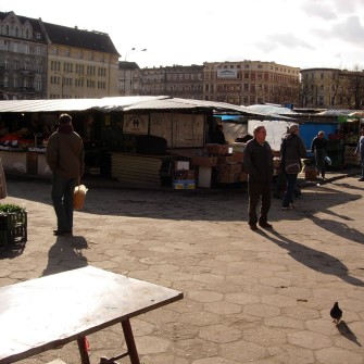 Targowisko powstało w 1947 roku po zamknięciu szaberplacu, który funkcjonował w tym samym miejscu. Z biegiem lat stało się jednym z najbardziej popularnych targów we Wrocławiu, przyciągającym wielu mieszkańców. W latach 90. XX wieku funkcjonowało pod rozłożonym namiotem cyrkowym „Goliat”. W 2006 roku zostało zamknięte, a na jego miejscu wybudowano Pasaż Grunwaldzki. Na fotografii jedna z alejek targowiska, a w tle budynki Manhattanu.