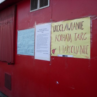 Targowisko powstało w 1947 roku po zamknięciu szaberplacu, który funkcjonował w tym samym miejscu. Z biegiem lat stało się jednym z najbardziej popularnych targów we Wrocławiu, przyciągającym wielu mieszkańców. W latach 90. XX wieku funkcjonowało pod rozłożonym namiotem cyrkowym „Goliat”. W 2006 roku zostało zamknięte, a na jego miejscu wybudowano Pasaż Grunwaldzki. Na fotografii plakaty protestacyjne przeci zamknięciu targowiska i odezwa kupców do władz miasta.