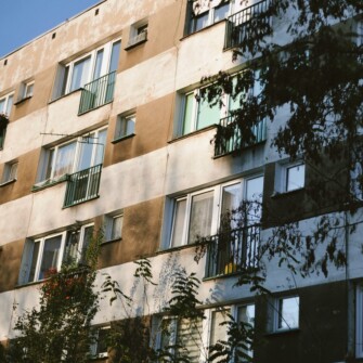 Na fotografii czteropiętrowy blok mieszkalny.