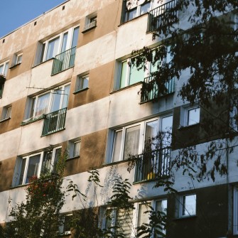 Na fotografii czteropiętrowy blok mieszkalny.